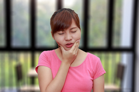 Woman hands touching her own cheek or having toothache - dental concept