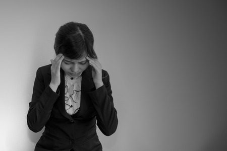 Business woman headache in black suit on black and white conceptの写真素材
