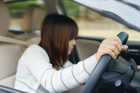 Young woman find something in drawer front of car with carelessness while driving - accident conceptの写真素材