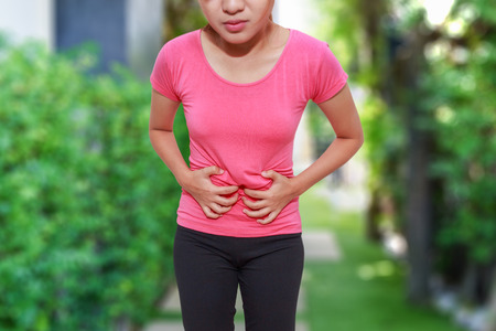 Asian woman touching her own belly with stomachache, appendicitis pain