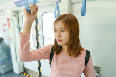 Woman traveler holding the train rails while taking sky train