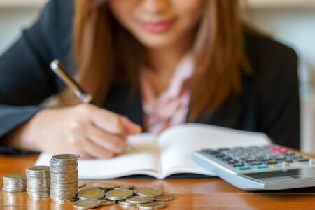 Stack money for growing chart of coins in font of businesswoman with calculatorの写真素材