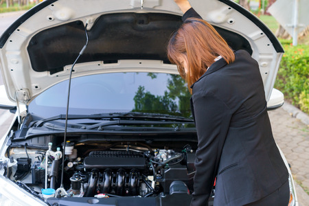 Business woman looking at motor with car breakdown