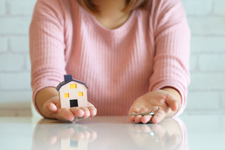 Real estate agent hand holding house key and house toyの写真素材