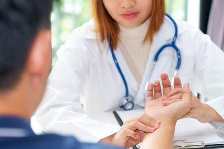 Doctor examining pulse of patient by hands, medical diagnosis conceptの写真素材