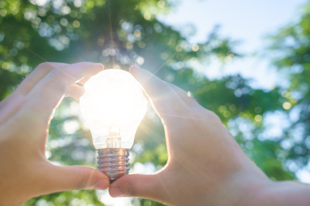 Woman hands holding light bulb with solar energy or thermal energy concept.の写真素材