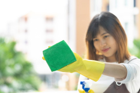 Woman housekeeper cleaning the mirror with yellow clothの写真素材