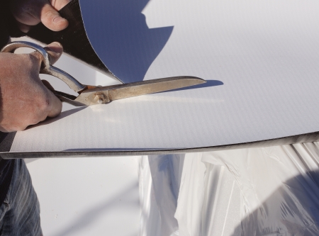 Construction site - cutting synthetic sheet PVC sealing coverの写真素材