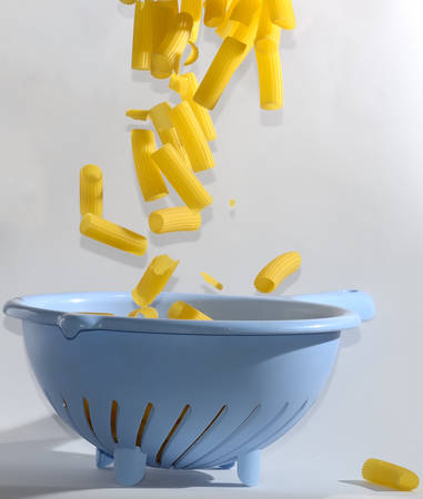 Rigatoni pasta being poured in colanderの写真素材