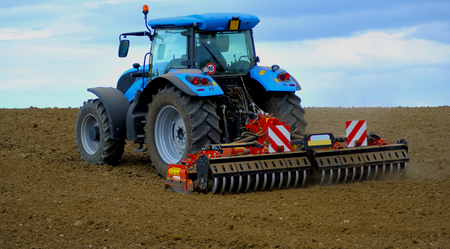 Agricultural Landscape - Tractor working on the field - summer sunny day