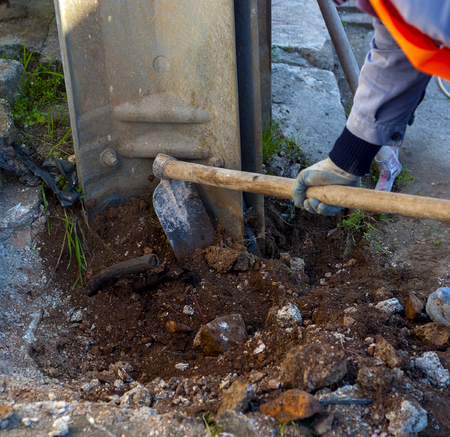 worker with hoe performs excavation work around an electricity poleの写真素材