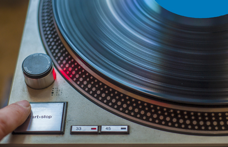 A fan of high-fidelity music starts the record player for listening to a vinylの写真素材