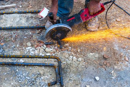 Construction worker cuts rebar circular saw on site. の写真素材