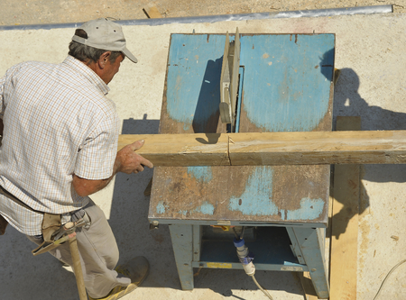 Carpenter cutting wooden planks with table sawの写真素材