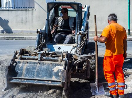 Worker checks the progress of the Milling of asphalt for road reconstruction accessory for skid steerの写真素材