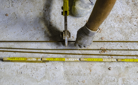 Worker is cutting reinforcement mesh with bolt cutters at building site.の写真素材