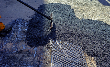 worker leveling fresh asphalt during asphalt pavement repair or construction worksの写真素材