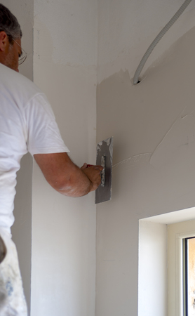 Worker using a putty knife, rear view.  Focused
Focus is on the tools.の写真素材