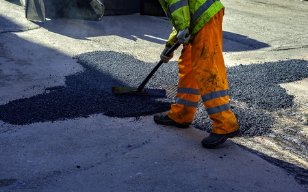 worker leveling fresh asphalt during asphalt pavement repair or construction worksの写真素材