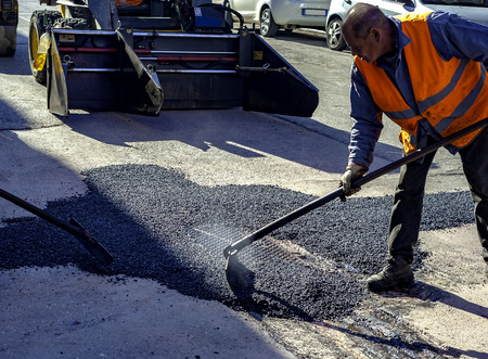 worker leveling fresh asphalt during asphalt pavement repair or construction worksの写真素材
