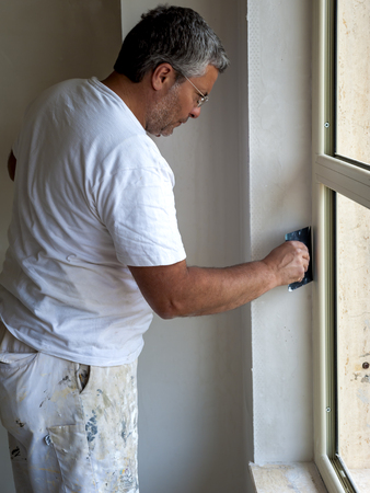 Worker using a putty knife, rear view.  Focused
Focus is on the tools.の写真素材