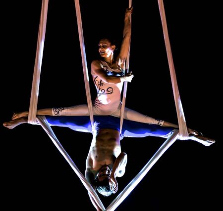 Bitonto, Italy - May 28, 2017: Acrobats perform a trick on slings suspended in the void and secured with harnesses on a festive evening in the main square of Bitonto, Pugliaのeditorial素材