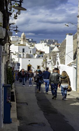 Alberobello, Italy - April 17, 2017: Tourists visit Alberobello, a small town and comune of the Metropolitan City of Bari. It has about 10,700 inhabitants and is famous for its unique trullo buildings.のeditorial素材
