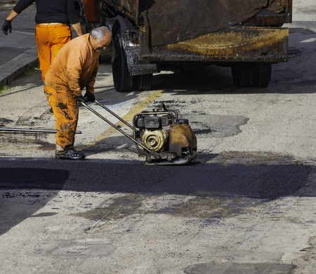 Compactor finishing the last phase of laying new asphalt to patch a bump in the road.の写真素材