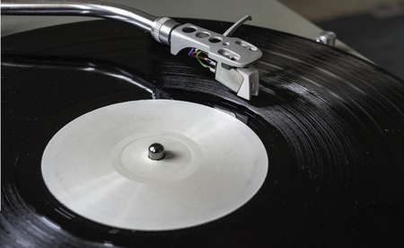 Closeup turntable player playing vinyl record disc. Focus on needle cartridge headshell. Hifi sound...