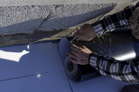 Worker cuts PVC sheet with a scissorsの写真素材