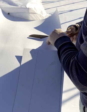 Worker cuts PVC sheet with a scissorsの写真素材