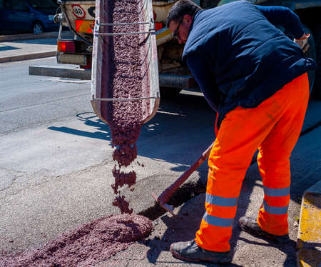 fiber optic cables buried in a micro trench with concrete colored red by a workerのeditorial素材