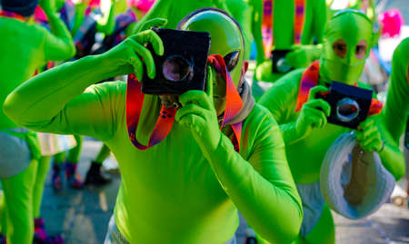 Masked young man with fake camera, beautiful and colorful clothes during the parade of masked groups in the streets of a city in Puglia. Italyのeditorial素材