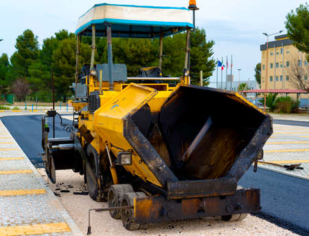 Tracked paver laying fresh asphalt pavement on top of the gravel base during road constructionの写真素材