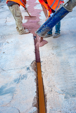 Filling with colored concrete of excavation with a narrow section for the implementation of a fiber optic distribution network for telecommunications.の写真素材