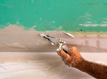 Worker with trowel and/or American trowel apply putty to the gypsum plasterboards with matched flapsの写真素材