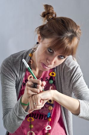 Young girl with pigtails, and colorful necklace laying and writes with a pen on her handの写真素材