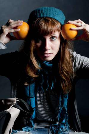 beautiful girl with scarf and hat and oranges on a black backgroundの写真素材