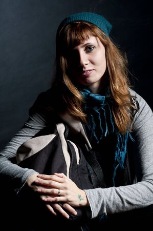 beautiful girl with scarf, hat and bag on a black backgroundの写真素材