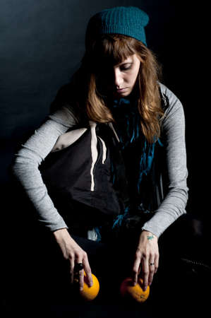 beautiful girl with scarf and hat and oranges on a black backgroundの写真素材