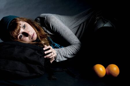 beautiful girl with scarf and hat and oranges on a black backgroundの写真素材
