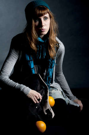beautiful girl with scarf and hat and oranges on a black backgroundの写真素材