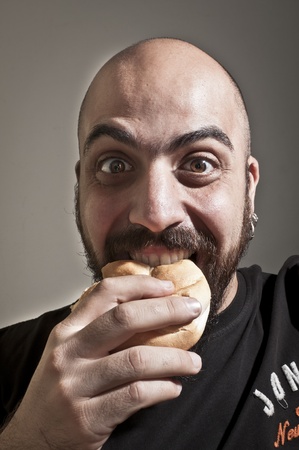 man with bread in his mouth on grey backgroundの写真素材