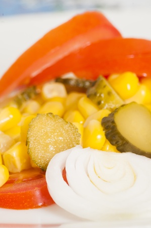 salad of tomatoes, onions, cucumbers and corn on a white plateの写真素材