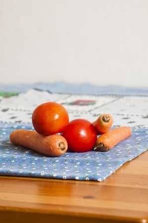 tomatoes and carrots on blue tablecloth on the tableの写真素材