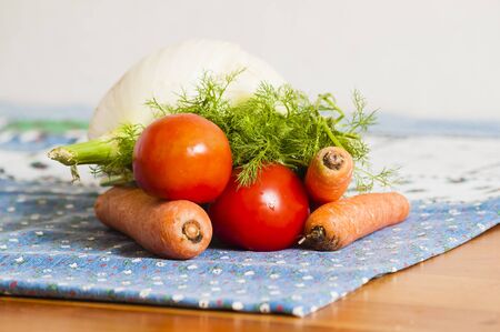 tomatoes, carrots and fennel on blue tablecloth on the tableの写真素材