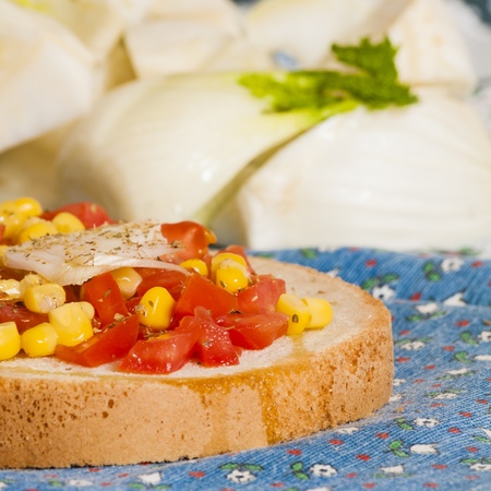 bruschetta with tomato, onion and corn on blue tablecloth with fennel and Brussels sproutsの写真素材