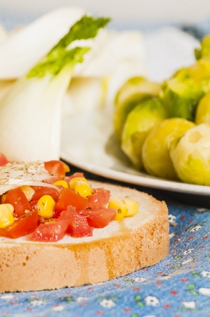 bruschetta with tomato, onion and corn on blue tablecloth with fennel and Brussels sproutsの写真素材