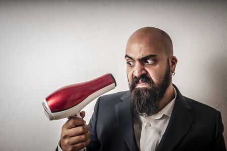 man bearded and jacket with hairdraier and funny expressions on white backgroundの写真素材
