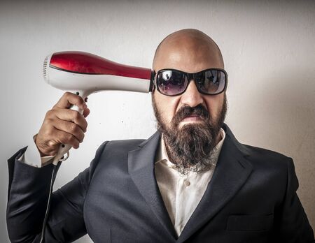 man bearded and jacket with hairdraier and funny expressions on white backgroundの写真素材